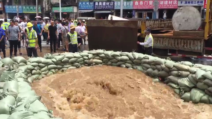 西湖路与湘江中路交汇处附近,救援人员正在用钢板堵住一处出水口